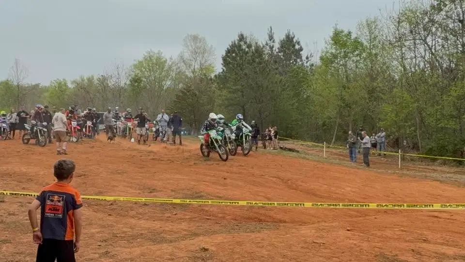 A young spectator watching from behind the tape as the mini riders gather at the start