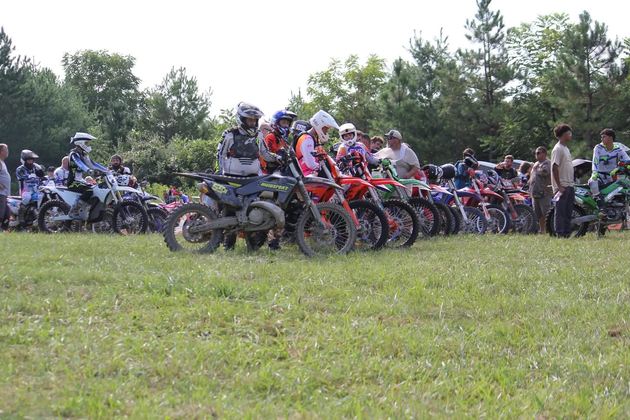 A long row of riders lined up on their bikes at the start, with spectators alongside